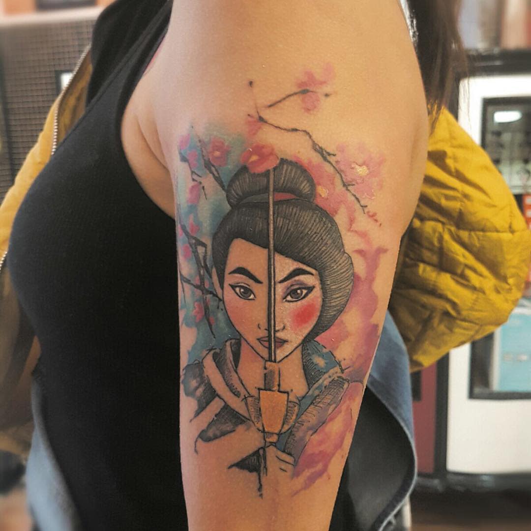 Colorful tattoo of Mulan with a sword on an upper arm